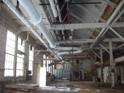 The room also contains the main steam pipe (overhead) entering Mill C from the Powerhouse.